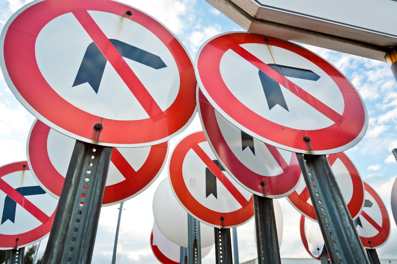 Multiple no left turn traffic signs displayed together under a blue sky.
